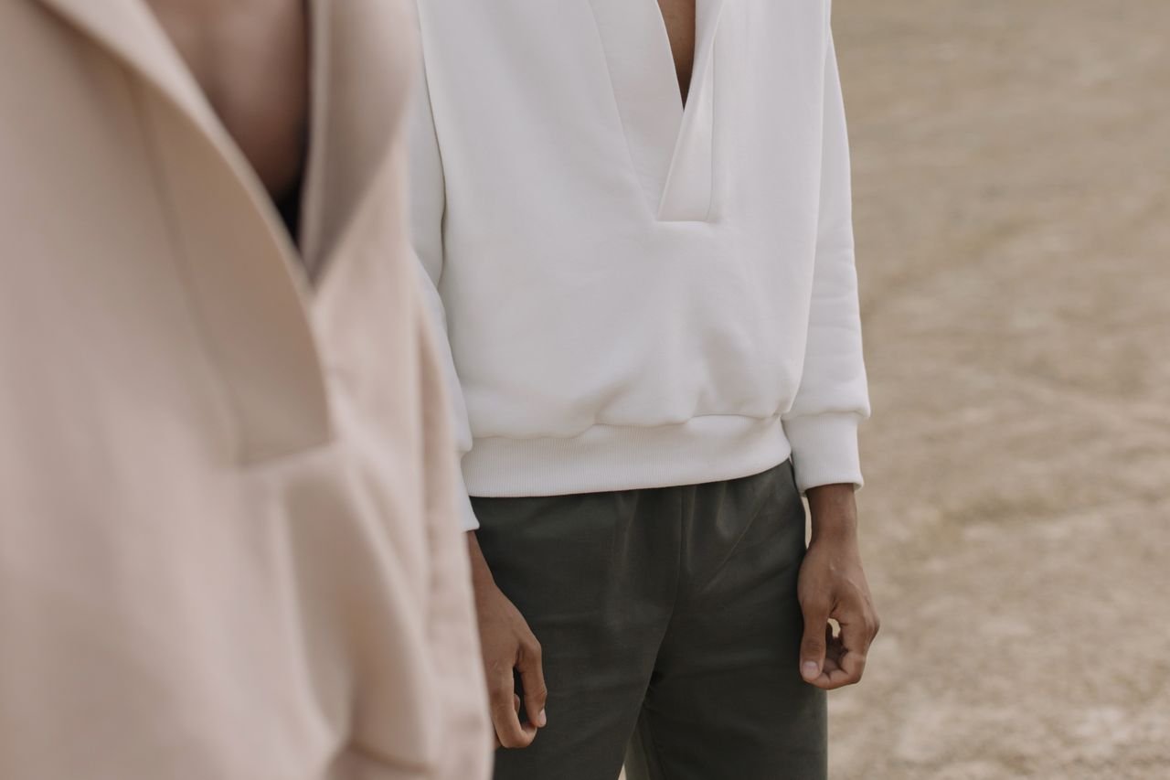Stylish mens casual wear featuring a white hoodie and green pants in a minimalist setting.